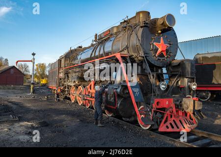 SORTAVALA, RUSSIE - 07 OCTOBRE 2021 : un ouvrier effectue l'entretien d'une vieille locomotive à vapeur soviétique dans une matinée ensoleillée d'octobre Banque D'Images