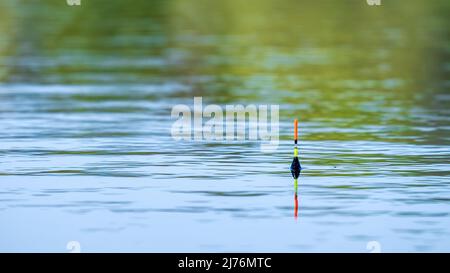 Flottez de pêche jaune-orange à la surface de l'eau Banque D'Images
