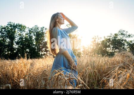 Connectez-vous à la nature, ralentissez, soyez présent, entrez dans vos sens. Paisible seule jeune femme en robe marchant sur le champ de blé au coucher du soleil le jour d'été Banque D'Images