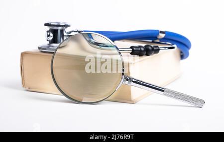 Livre avec stéthoscope et loupe. Éducation médicale, recherche d'informations sur la médecine, les problèmes de santé et le traitement. Photo de haute qualité Banque D'Images