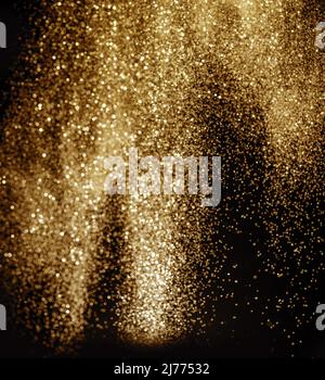 Golden Dust - poudre d'or étincelante sur fond noir. Banque D'Images