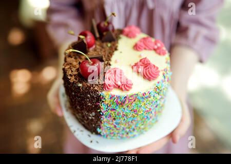 Délicieux gâteau d'anniversaire maison aux deux côtés. Magnifique gâteau au chocolat et à la cerise recouvert de copeaux de chocolat. Délicieux gâteau rose clair avec sp. Coloré Banque D'Images