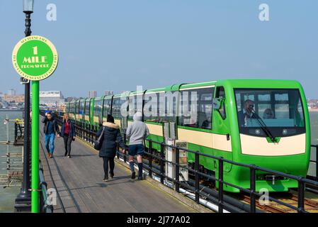 Tout nouveau train électrique Southend Pier qui a récemment été mis en service. Les personnes qui marchent sur la passerelle, passent devant un marqueur de 1 kilomètres. Long quai Banque D'Images