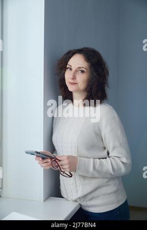 Une élégante femme d'âge moyen avec un smartphone entre ses mains. Banque D'Images