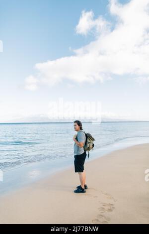 Homme amérindien portant un sac à dos sur la plage de Maui H. Banque D'Images