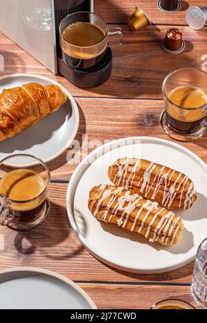 café en capsules et dans une tasse, pâtisseries fraîches sur une table en bois Banque D'Images