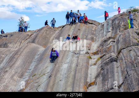 Personnes jouant à la forteresse de Sacsayhuaman formation de pierre naturelle utilisée comme un toboggan, ville de Cusco, Vallée Sacrée, Pérou Banque D'Images