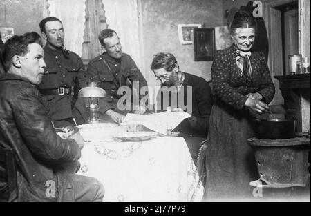 Trois soldats sont assis autour d'une table à manger dans une maison en France en WW1. Une fois que les troupes sont entrées dans un village, elles sont souvent logées avec des familles locales. Banque D'Images