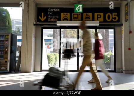 06 mai 2022, Espagne, Palma: Les personnes avec des valises marchent devant un panneau de location de voiture à l'aéroport de Palma de Majorque. Il y a beaucoup moins de voitures de location à Majorque qu'avant le début de la pandémie de Corona. Photo: Clara Margais/dpa Banque D'Images