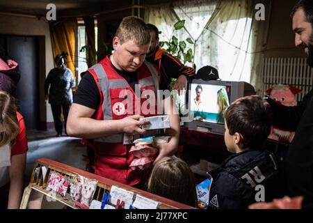 26 avril 2022, Kharkiv, Kharkivs'ka Oblast', Ukraine: Le personnel de la Croix-Rouge distribue de la nourriture aux enfants et à leur père dans un immeuble à Kharkiv. Malgré les bombardements constants des troupes russes qui encerclent la ville de Kharkiv, les professionnels de la santé et les bénévoles de la Croix-Rouge ont poursuivi leurs travaux de 24/7 pour sauver des vies et aider les personnes dans le besoin. (Image de crédit : © Alex Chan TSZ Yuk/SOPA Images via ZUMA Press Wire) Banque D'Images