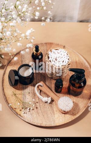 Bouteilles cosmétiques, brosse pour le visage et bâtons d'oreilles sur plateau en bois Spa et bien-être, concept zéro déchet. Vue de dessus. Banque D'Images