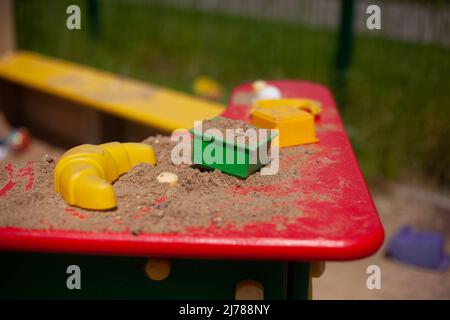 Moules de sable sur l'aire de jeux. Articles pour les enfants. Détails de la zone des enfants dans la cour. Moule carré pour sculpter le sable. Côté rouge du bac à sable. Banque D'Images