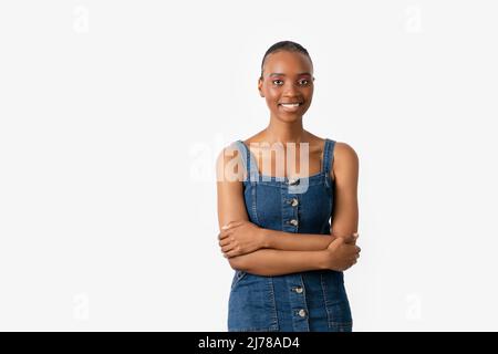 Jeune et jolie femme de peau sombre isolée sur fond blanc croisant ses bras et regardant un point avec un visage souriant. Photo de haute qualité Banque D'Images