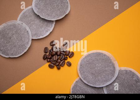 Vue de dessus des dosettes de café et des grains de café sur du carton orange et brun à 45 degrés comme exemple de différents produits crus de café. Plan de pose co Banque D'Images