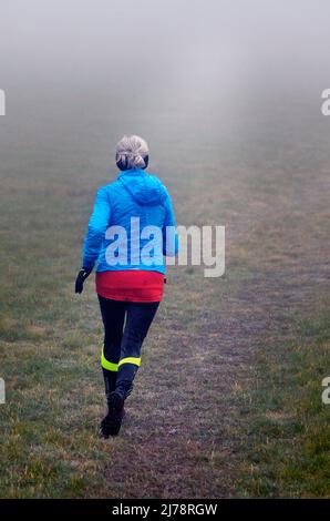 femme âgée solitaire en train de courir sur le champ de la brume Banque D'Images