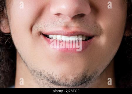 Gros plan photo d'un visage souriant et de la bouche d'un jeune homme, beau et barbu. Photo de haute qualité Banque D'Images