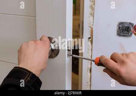 Le serrurier installe la serrure de porte dans la maison. Banque D'Images