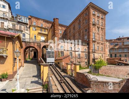 Mondovì, Italie - 29 avril 2022 : funiculaire arrivant à la gare centrale de rione Piazza avec des bâtiments anciens, le funiculaire relie la rue Breo Banque D'Images