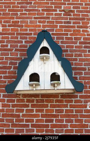 Pigeonnier triangulaire d'époque avec trois entrées sur un mur de briques Banque D'Images