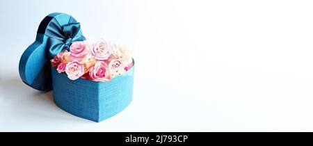 Boîte cadeau et bouquet en forme de coeur. Fleurs un cadeau en forme de coeur. Roses dans une boîte coeur sur fond rose Banque D'Images