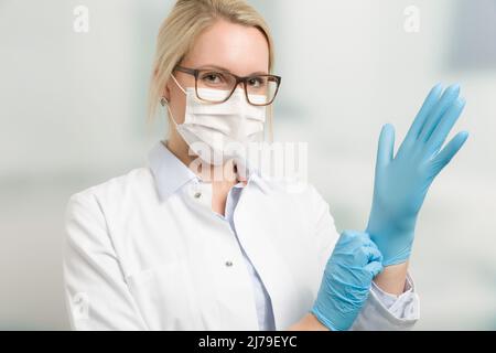 femme médecin avec un masque médical et des gants médicaux devant une salle de clinique Banque D'Images