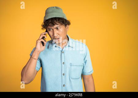 homme asiatique choqué en parlant sur son smartphone Banque D'Images