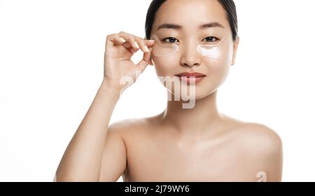 Gros plan du visage de femme asiatique avec des taches sous les yeux des cercles sombres et de la peau fatiguée. Fille touchant la peau propre avec le maquillage naturel et l'utilisation Banque D'Images