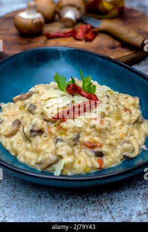 Risotto aux champignons et aux tomates séchées dans un bol bleu Banque D'Images