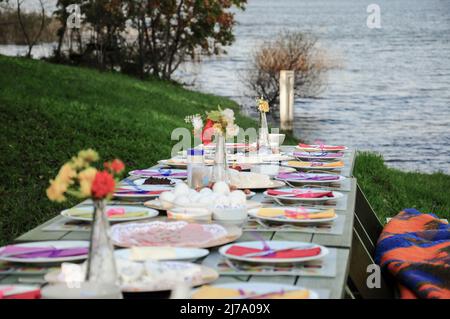 Une table de pique-nique chic pleine de nourriture au bord du lac en été Banque D'Images