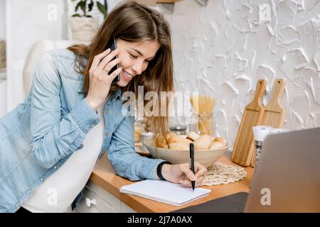 Portrait d'une femme indépendante attirante parlant au téléphone avec un collègue et enregistrant des moments au travail et utilisant un ordinateur portable. Une belle entreprise Banque D'Images