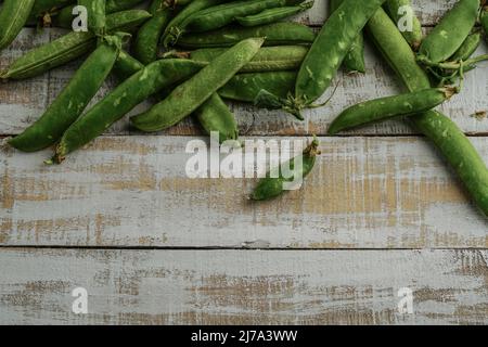 pile de petits pois frais sur une table en bois Banque D'Images