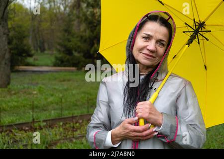 Santé mentale senior bien-être, comment améliorer la cognition et l'émotion. La santé mentale des personnes âgées. Bonne senor femme en imperméable jaune appréciant Banque D'Images