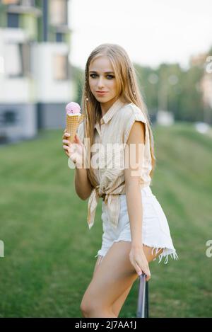 Une femme mange de la glace douce à l'extérieur dans le parc Banque D'Images