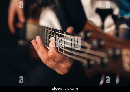 Gros plan de doigts de sexe masculin jouant cinq guitares de basse électrique à cordes Banque D'Images