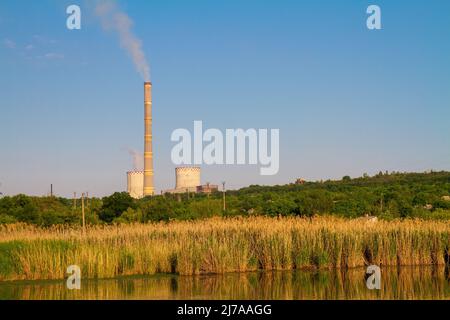 Centrale de cogénération (centrale thermique et électrique combinée). Centrale thermique avec conduit de fumée. Paysage industriel avec eau, arbres et lignes électriques Banque D'Images