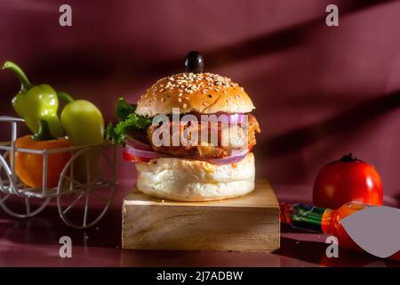 Hamburger au poulet avec tomate, ketchup et piment vert isolé sur un panneau de bois, vue latérale sur la restauration rapide américaine Banque D'Images