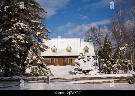 Ancienne maison en rondins de style Canadiana 1800s protégée par une clôture rustique en bois perchoir en hiver. Banque D'Images