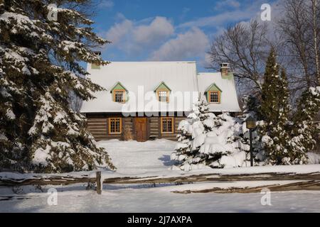 Ancienne maison en rondins de style Canadiana 1800s protégée par une clôture rustique en bois perchoir en hiver. Banque D'Images