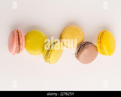 Macarons français pastel dans un vol gelé sur fond blanc. Composition festive. Anniversaire, date romantique, nourriture sucrée, calories. Annontis Banque D'Images