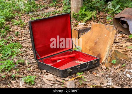 Une valise vide rouge et noire abandonnée dans la nature Banque D'Images