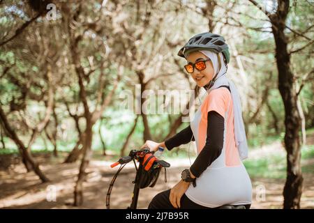 jolie fille voilée dans des lunettes de soleil portant des écouteurs vélo Banque D'Images