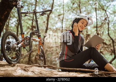 une jeune fille voilée assise avec des écouteurs qui écoutent de la musique tout en faisant du vélo Banque D'Images