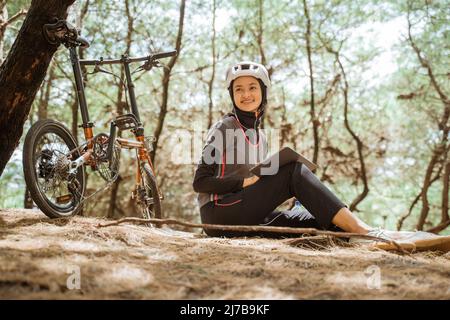 une fille voilée assise avec des écouteurs et utilisant une tablette pendant le vélo Banque D'Images