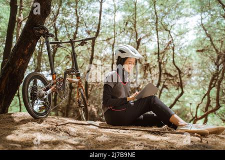 fille voilée assis au repos vélo portant des écouteurs et utilisant la tablette Banque D'Images