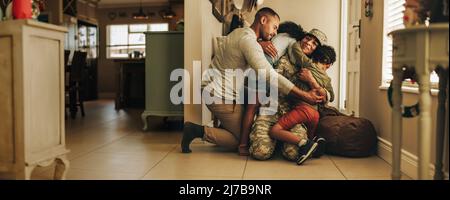 Accueil militaire tant attendu. Une femme soldat se réunirait avec son mari et ses enfants après avoir servi dans l'armée. Un servicewoman joyeux qui l'embrasse Banque D'Images