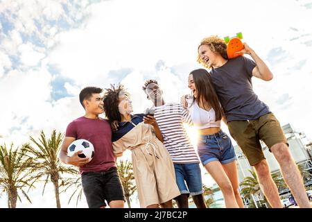 Groupe Uni de jeunes amis adultes multiethniques riant ensemble en plein air Banque D'Images
