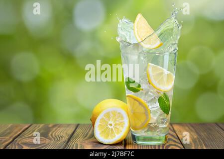 limonade en verre avec éclaboussures sur une table en bois Banque D'Images