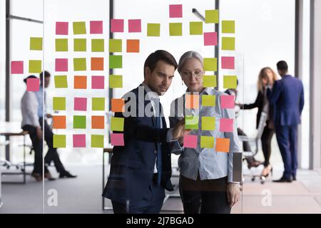 Deux employés de bureau sérieux utilisant la méthode de la mêlée, l'analyse du projet Banque D'Images