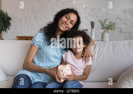 Bonne mère et petite fille tenant une tirelire en céramique Banque D'Images