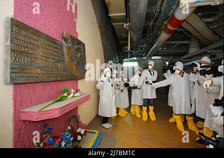 Journalistes se tenant près du monument aux liquidateurs de Tchernobyl situé à l'intérieur de la construction de la centrale nucléaire de Tchernobyl. Presse-tour à ChNPP pour la masse Banque D'Images